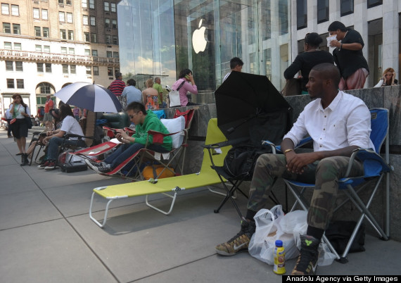 People sit in front of an Apple store (59th St & 5th avenue intersection NY)